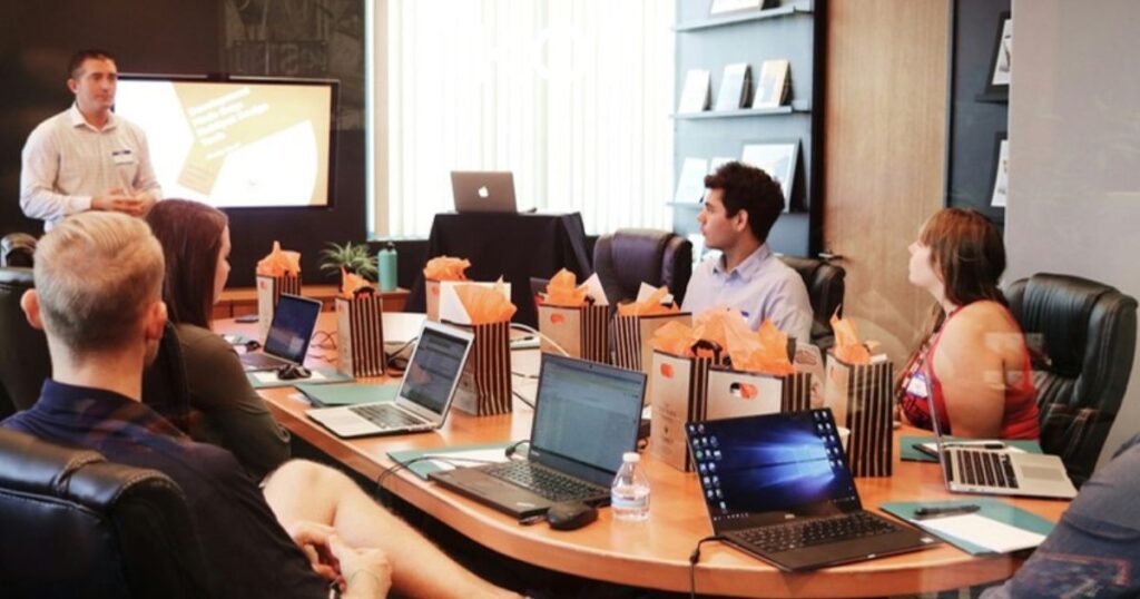 Equipo en reunión de planificación con laptops y presentación de proyectos para Project Manager coordinador de proyectos digitales Full Time remoto en KOM Agencia Digital.